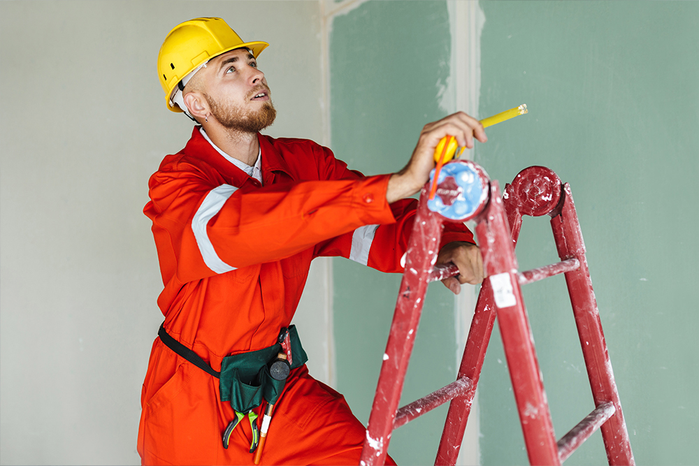 Young man in workwear using pliers while installing water filtration system